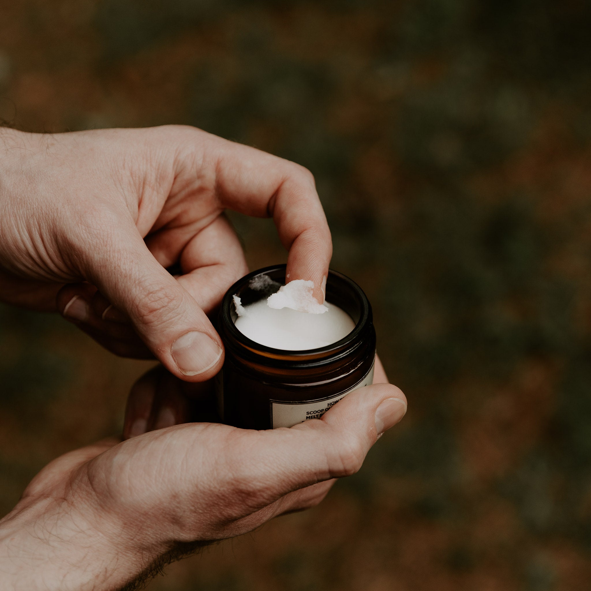 Person scooping Weatherbeard Supply Co Beard Butter out of jar with finger, showing off the smooth texture