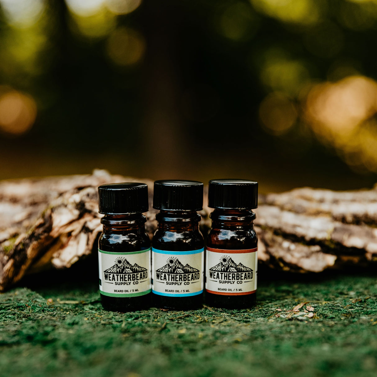 Weatherbeard Supply Co beard oil samples displayed in a natural setting, showcasing their outdoor-inspired scents.