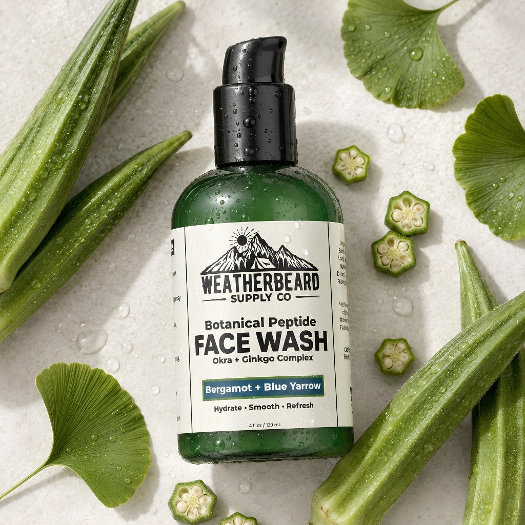 Weatherbeard Supply Co. Botanical Peptide Face Wash in a green bottle with a black pump, surrounded by fresh green okra and ginkgo leaves on a light stone background.