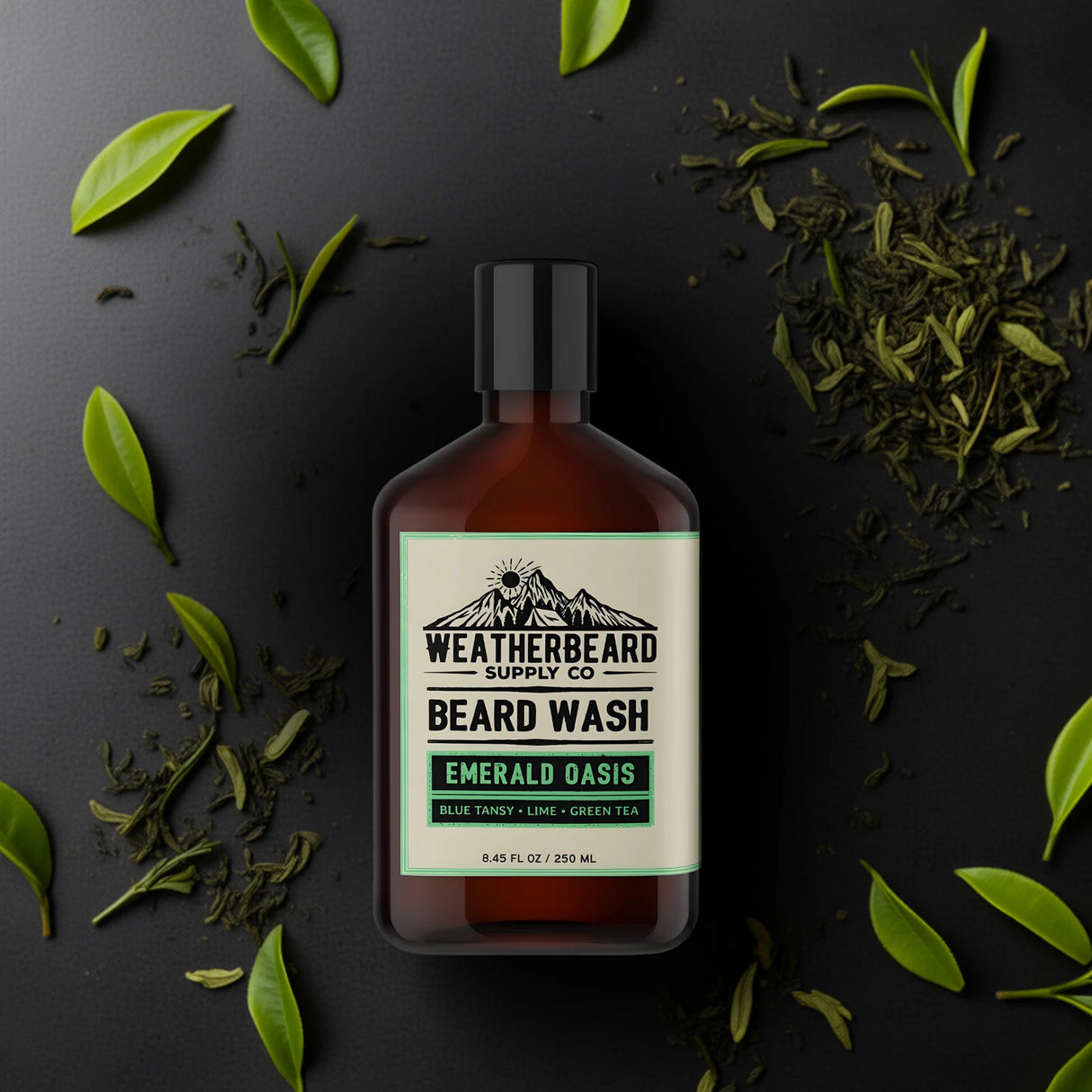 Bottle of Weatherbeard Supply Co. Emerald Oasis Beard Wash with green tea leaves on a dark background