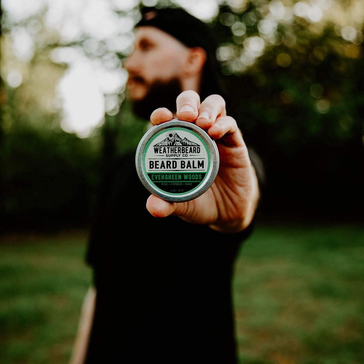Person holding Evergreen Woods Beard Balm in nature by Weatherbeard Supply Co