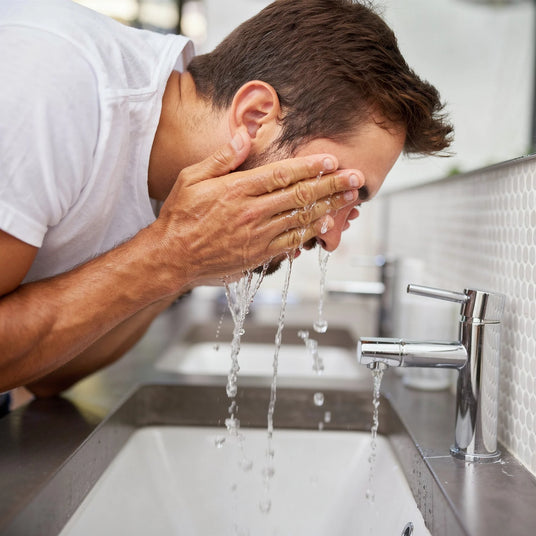 Man washing his face at bathroom sink