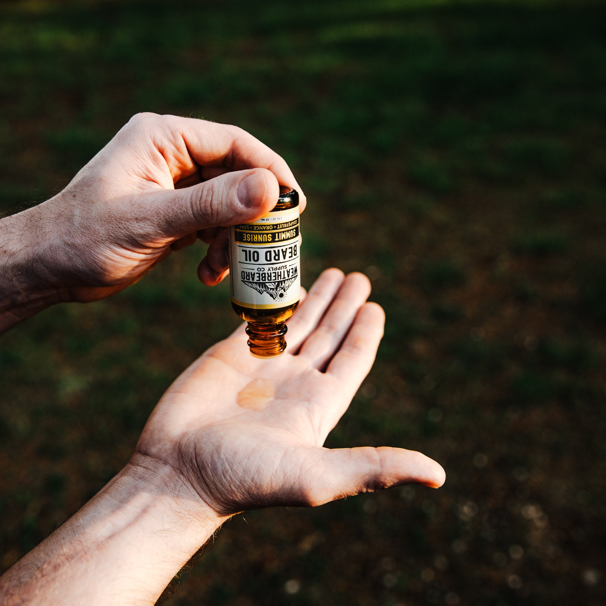 Person pouring Summit Sunrise Beard Oil into palms of hand
