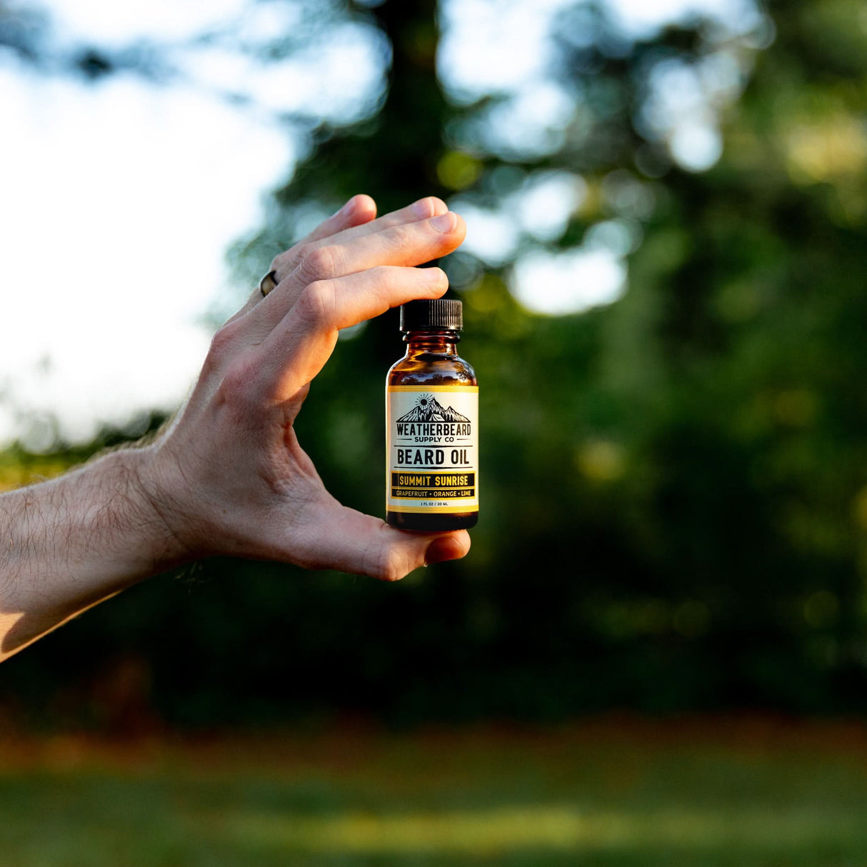 Person showcasing Summit Sunrise Beard Oil in nature
