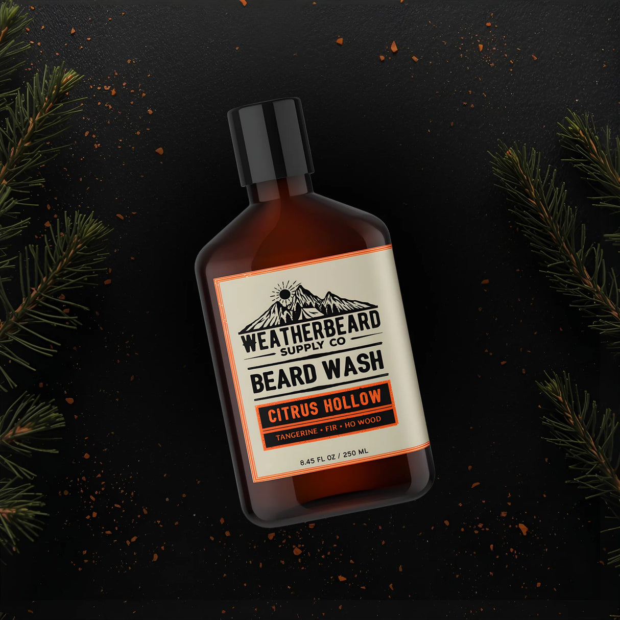 Bottle of Weatherbeard Supply Co. beard wash with a dark background and fir needles surrounding it
