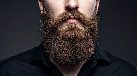 Man with thick beard wearing a black shirt against dark background