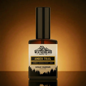 Bottle of Weatherbeard Supply Co Amber Trail spray parfum on a reflective surface with a warm brown background.