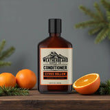 Bottle of Weatherbeard Supply Co. Citrus Hollow beard conditioner with tangerines and fir needles on a wooden surface.