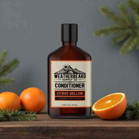 Bottle of Weatherbeard Supply Co. Citrus Hollow beard conditioner with tangerines and fir needles on a wooden surface.