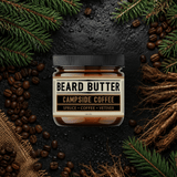 Jar of  'Campside Coffee'beard butter surrounded by coffee beans and pine branches on a dark background.