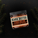Jar of Citrus Hollow Beard Butter on a black background with fir needles surrounding it