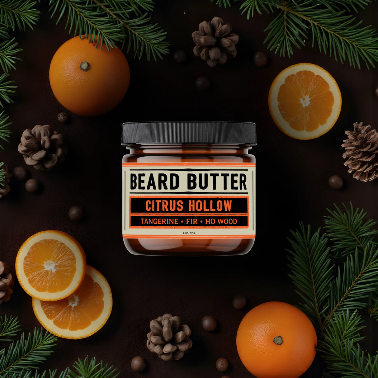 Jar of Citrus Hollow Beard Butter surrounded by tangerines and pine cones on a dark background