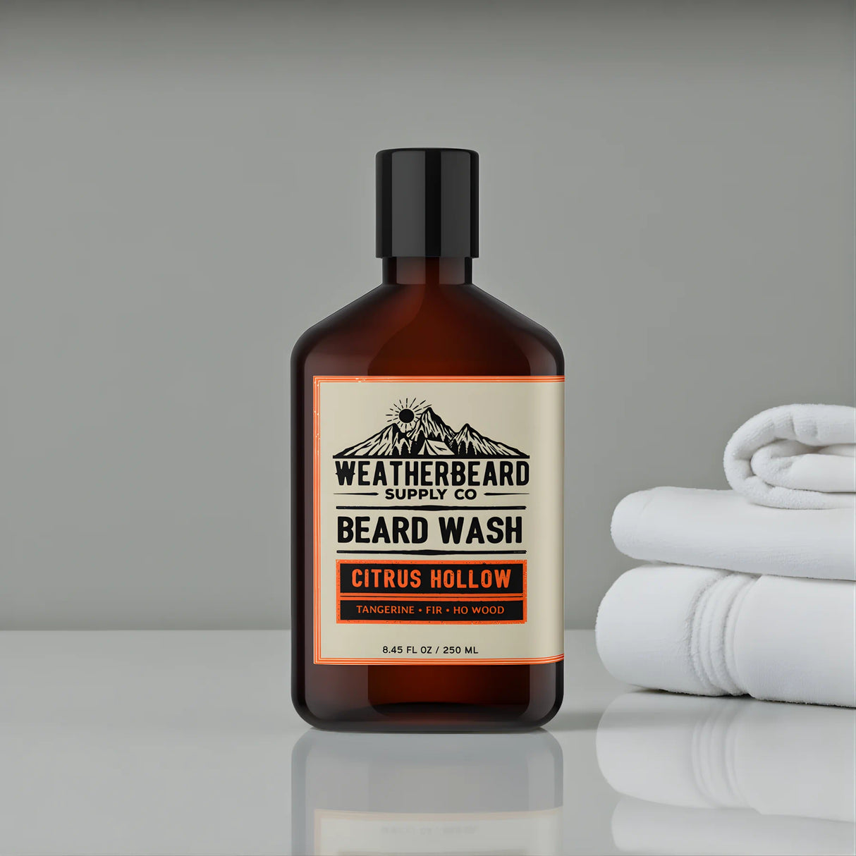 Bottle of Weatherbeard Citrus Hollow Beard Wash Sitting On A Bathroom Counter With Towels