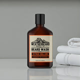 Bottle of Weatherbeard Citrus Hollow Beard Wash Sitting On A Bathroom Counter With Towels