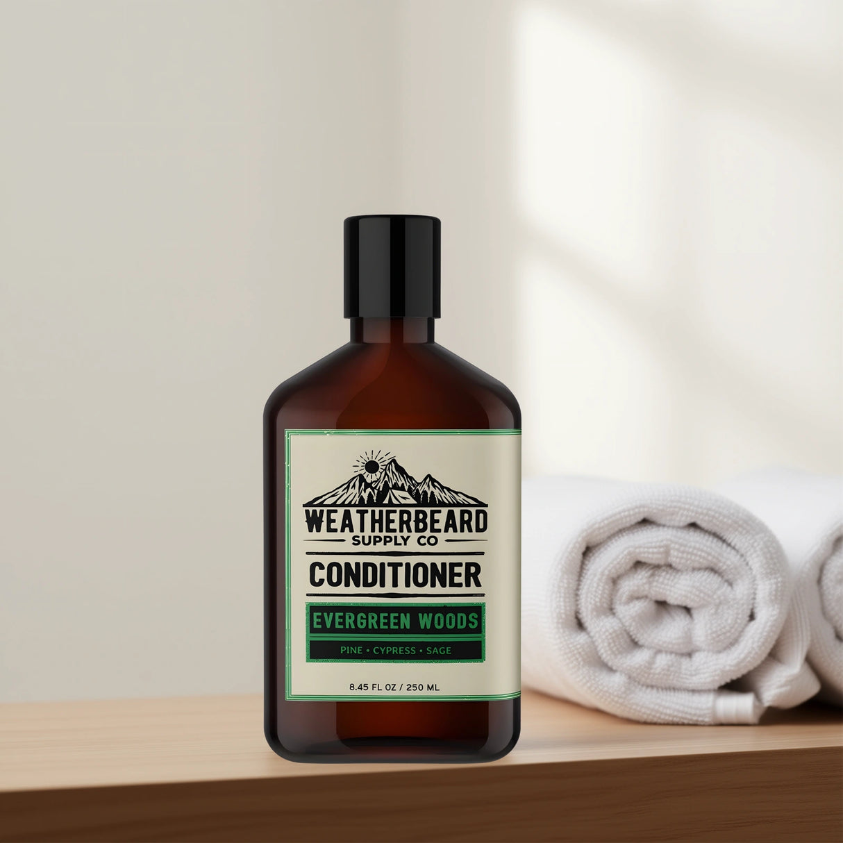 Bottle of Weatherbeard Supply Co. Evergreen Woods Beard Conditioner on a wooden surface with towels in the background.