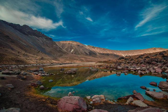 Mountainous landscape with a clear blue lake and rocky terrain.