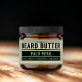 Jar of beard butter labeled 'Palo Peak' on a wooden surface with a dark background