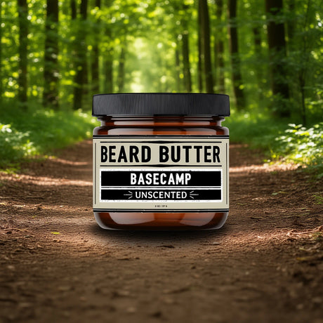 Jar of beard butter labeled 'Basecamp Unscented' in a forest setting