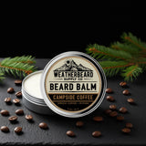 Campside Coffee Beard balm container with 'Weatherbeard Supply Co' branding on a dark surface with coffee beans and pine branches.