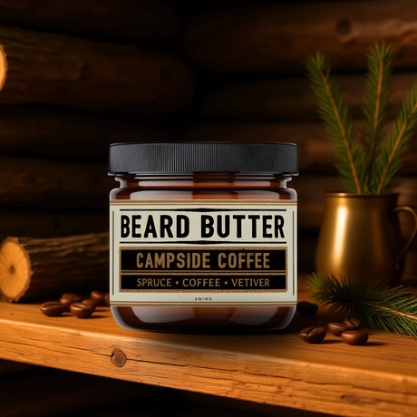 Jar of Weatherbeard Supply Co's Campside Coffee Beard Butter on a wooden surface with coffee beans and spruce