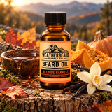 A bottle of Weatherbeard Supply Co Beard Oil stands on a tree stump outdoors, surrounded by autumn leaves, pumpkin pieces, vanilla beans, a bowl of honey, and a white orchid flower. The background shows blurred mountains at sunset.