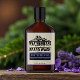Bottle of Weatherbeard Supply Co. Northern Wind Beard Wash on a wooden surface with blurred greenery and lavender petals in the background.