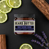 Jar of 'Northern Wind' Beard Butter with bergamot slices, lavender, and wood on a dark background